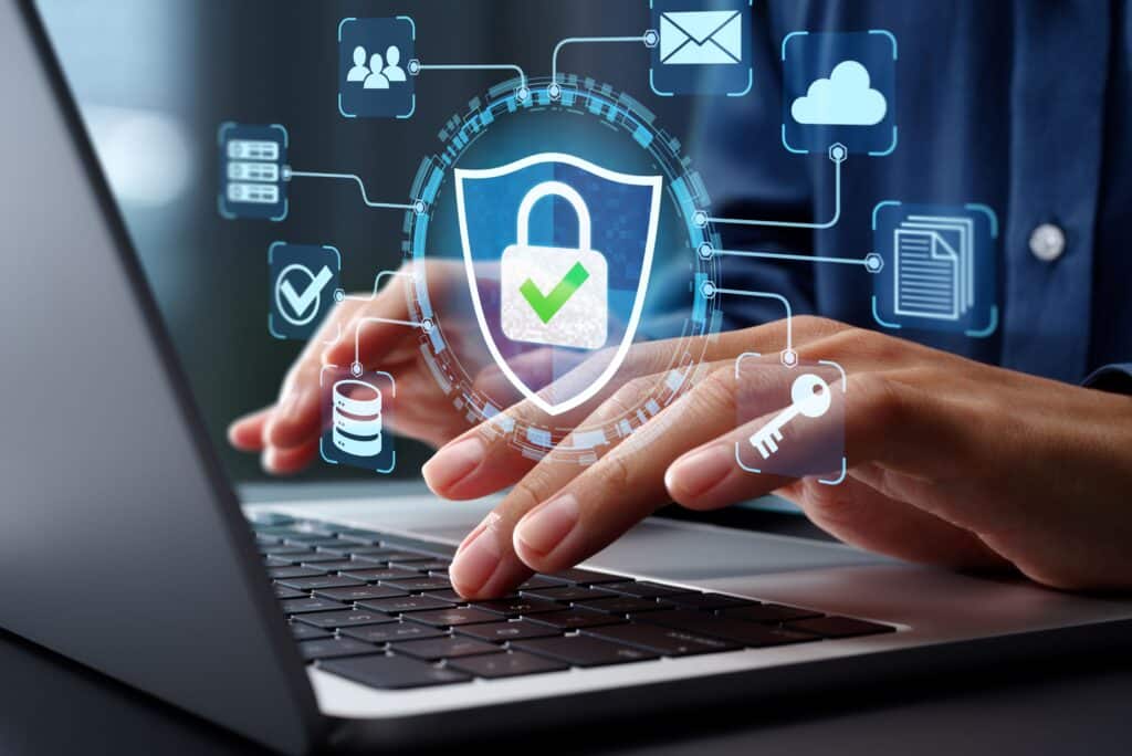 Business professional using a laptop with digital cybersecurity symbols representing data protection and online security.
