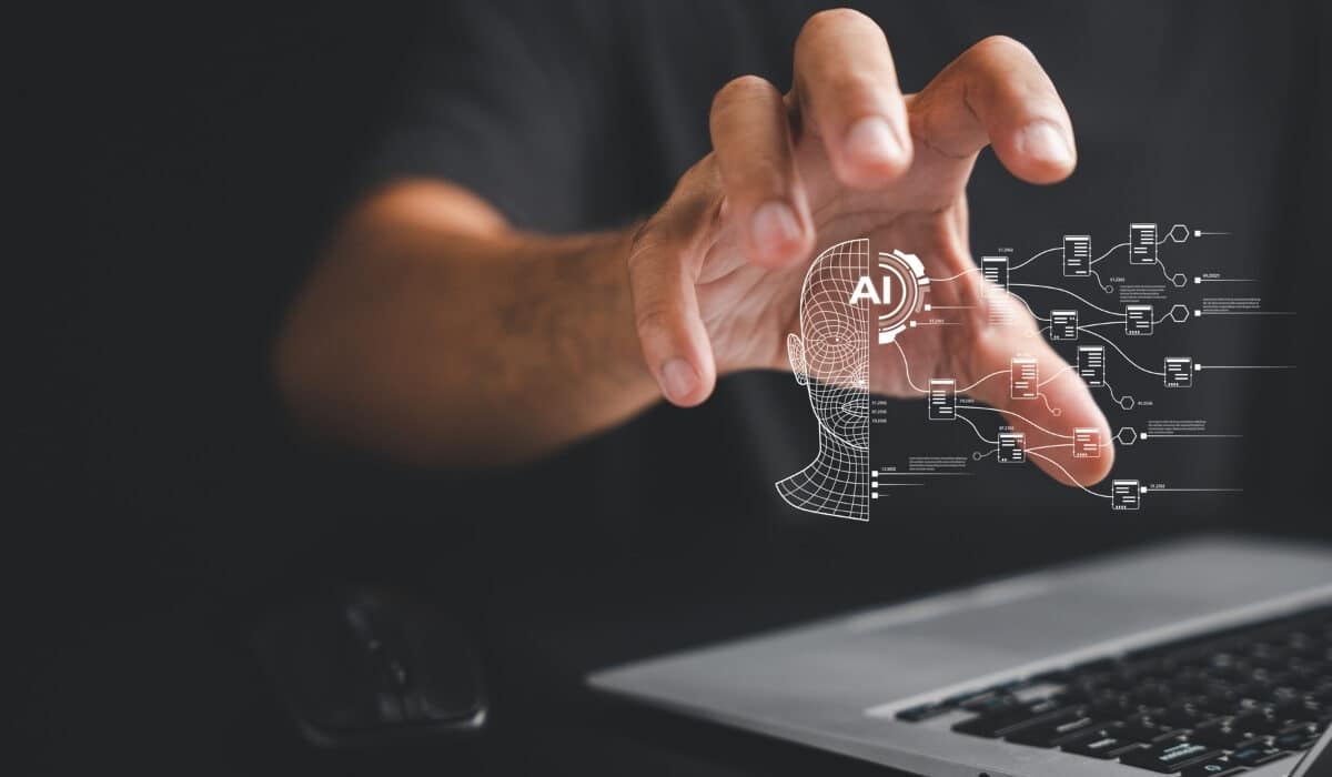 An image of a persons hand holding a digitalised person with the words AI written on them, showcasing how AI has become a vital part of modern work environments.